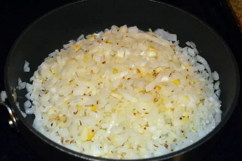 onions for spicy tomato curry simmering with seeds