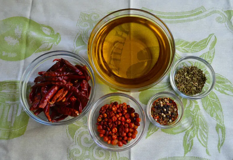 View of ingredients - olive oil, chili peppers, peppercorn, chili pequin, dired fenugreek seeds