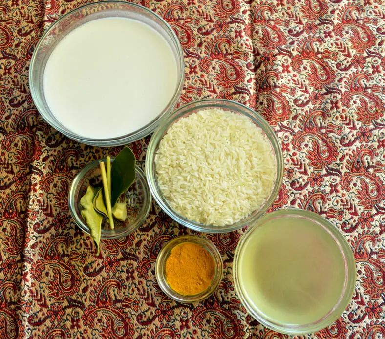 View of ingredients - rice, turmeric powder, coconut milk, vegetable broth, pandanus leaves