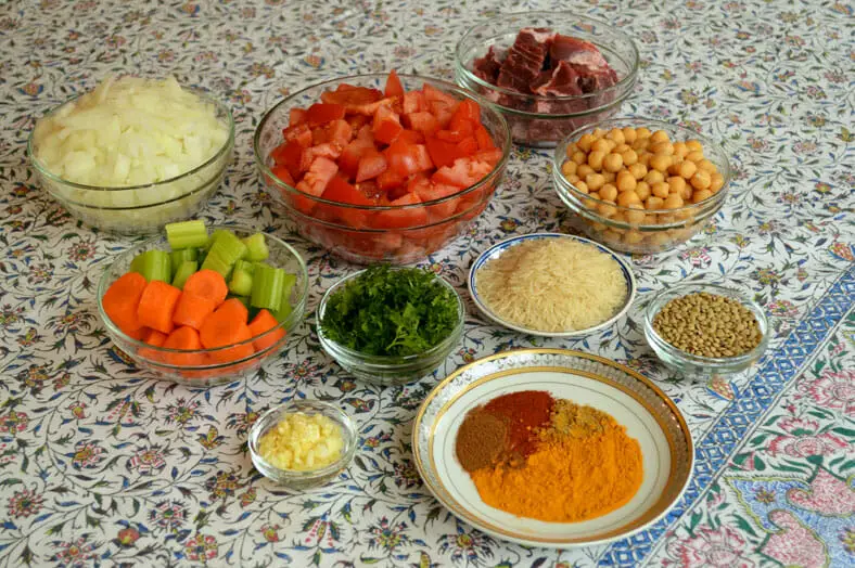 View of ingredients - tomatoes, carrots, onions, beef, spices, garlic, rice, dried lentils, vegetable stock, cooked chickpeas