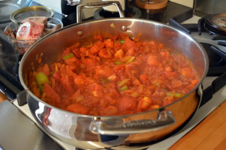 Adding tomatoes and all ingredients to the pan for stew