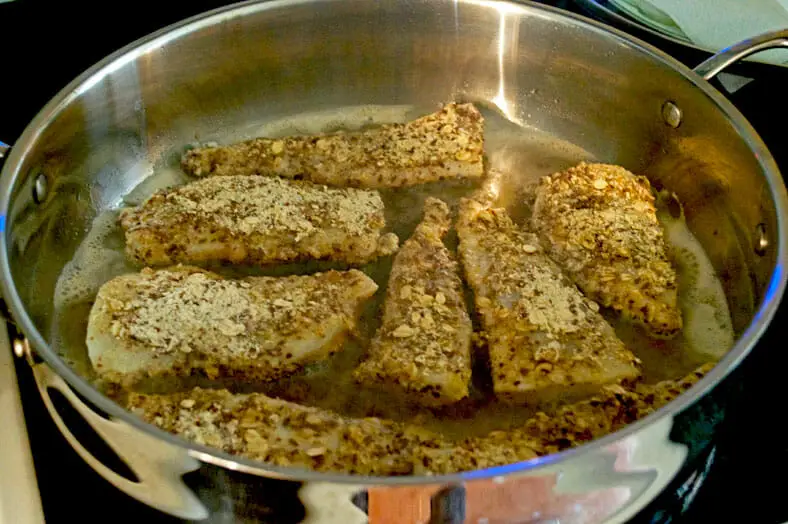 The fiskefilet frying in oil prior to being topped with remoulade
