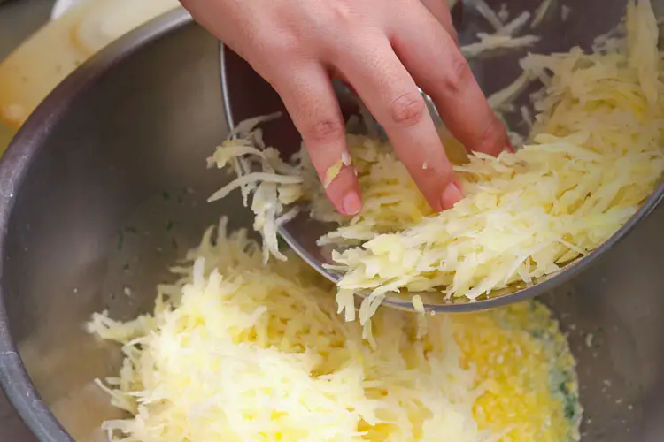 Adding grated potatoes to eggs for base after removing excess water