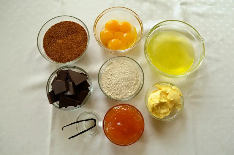 View of ingredients - butter, eggs, pastry flour, apricot jam, chocolate pieces, vanilla pod