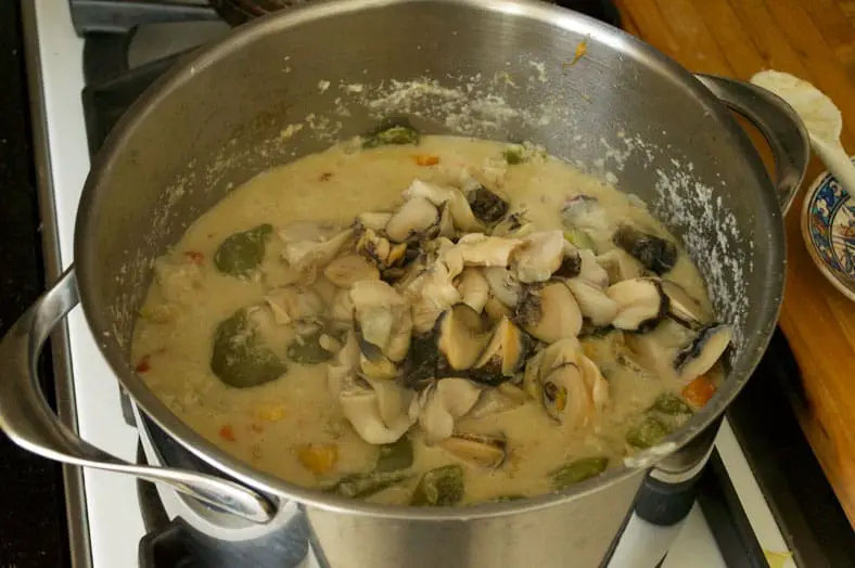 Adding conch to the vegetable mixture for cooking