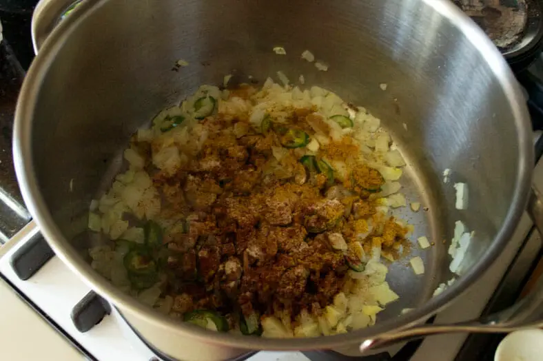 Adding onions, spices to the pot for cooking