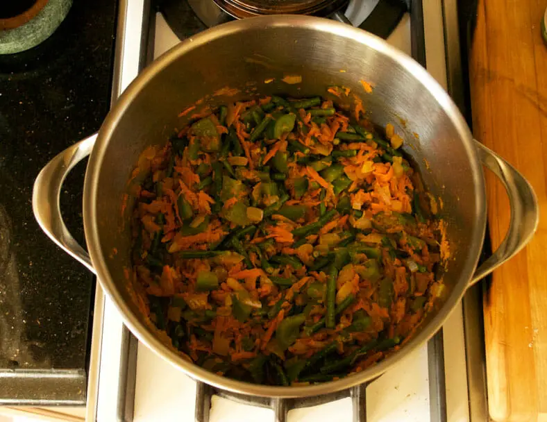 Adding carrot and green beans to the vegetable mixture