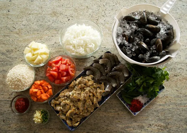 View of ingredients - tomatoes, shrimps, mussels, rice, carrots, clams, tomato paste