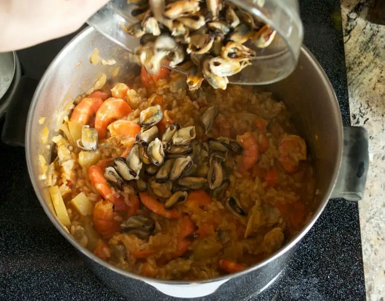 Adding clams and shrimps to the cooked rice 