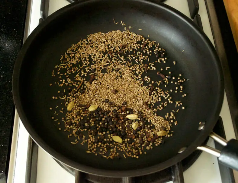 Roasting cardamom, black pepper, cumin seeds in a pan