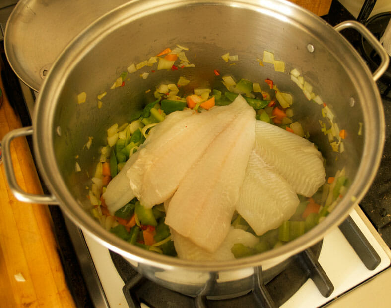 Adding fish fillet to the vegetables
