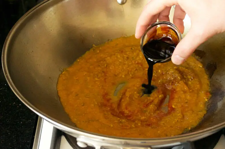 Adding soy sauce to the paste in kadai