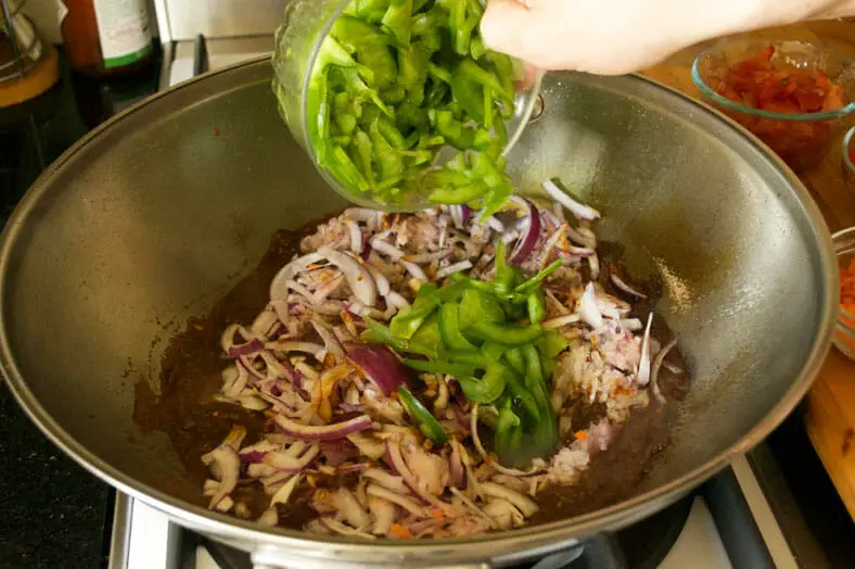 Adding sliced onions, bell peppers to the mixture