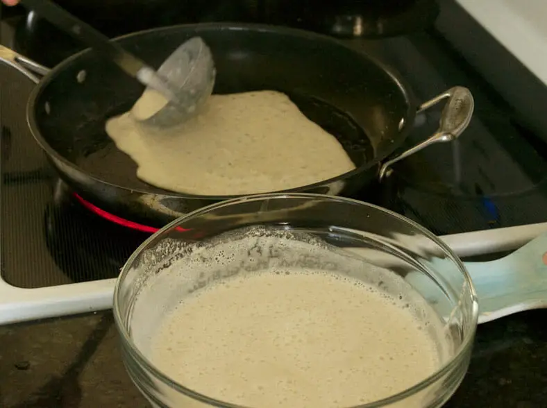 Once you pour your rice flour batter into the pan, it's important to try and spread it as evenly as possible while you still can! From there, it's very simple to cook your chatamari (Nepali rice flour crepe)