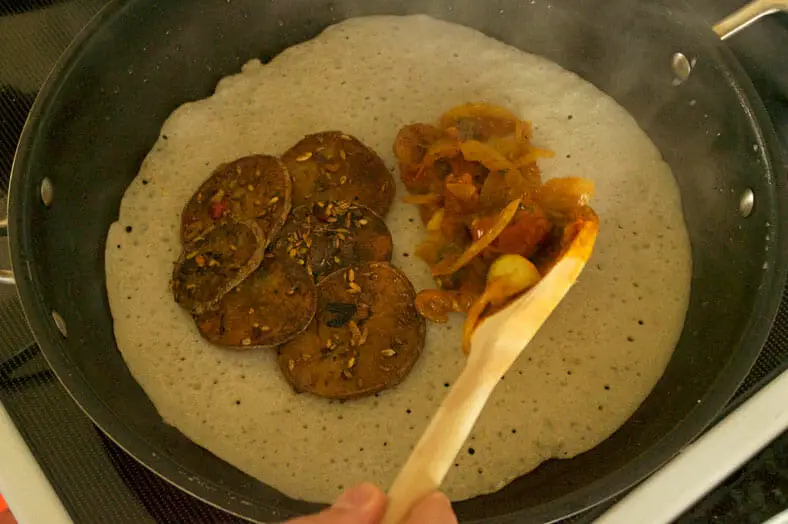 Once your chatamari (Nepali rice flour crepe) has had some time to cook, then you'll add your toppings before covering and allowing to steam for a few minutes. Yum!