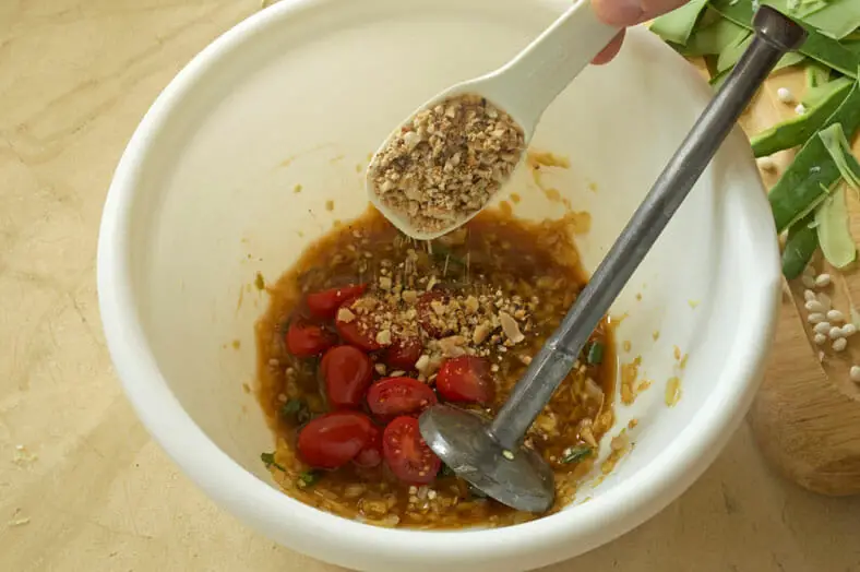 Adding crushed peanuts to chili pepper and garlic mixture
