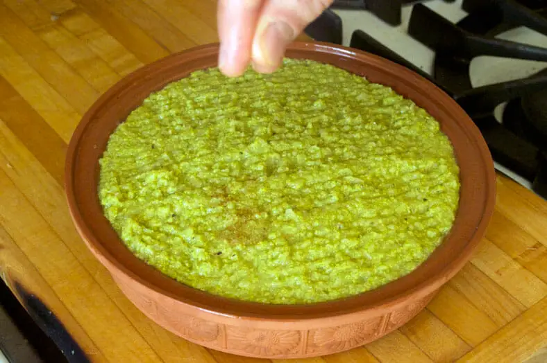 Sprinkling coconut sugar over the corn mixture and vegetarian filling of the Chilean pastel de choclo (corn pie) before placing it in the oven to bake