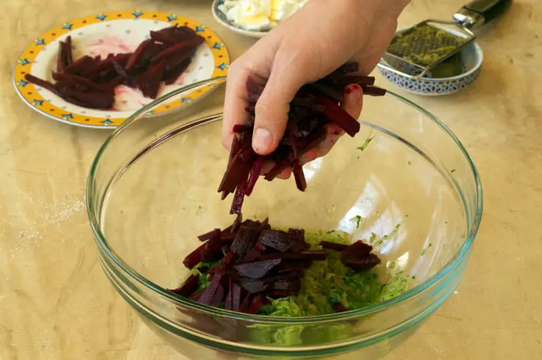 Adding fresh beets to grated gerkin pickles in bowl