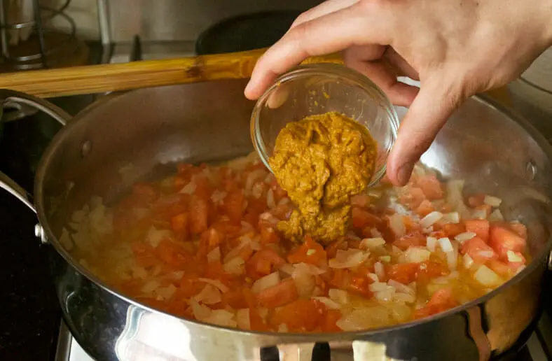Adding peri peri to the simmering for Mozambique Caril de Caranguejo (Crab Curry)
