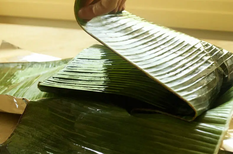 Closing the banana leaf stuffed with yam onion prawns and tomato for the dish
