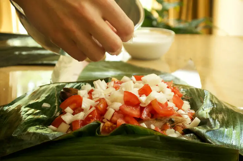 Stuffing a banana leaf with grated coconut 
