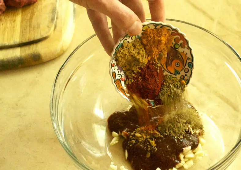 Adding the spices into the marinade for Anticuchos, or Peruvian beef kabobs