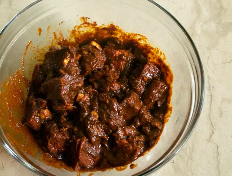 The Peruvian beef kabobs Anticuchos marinating in a bowl of marinade with Aji Panca as the base