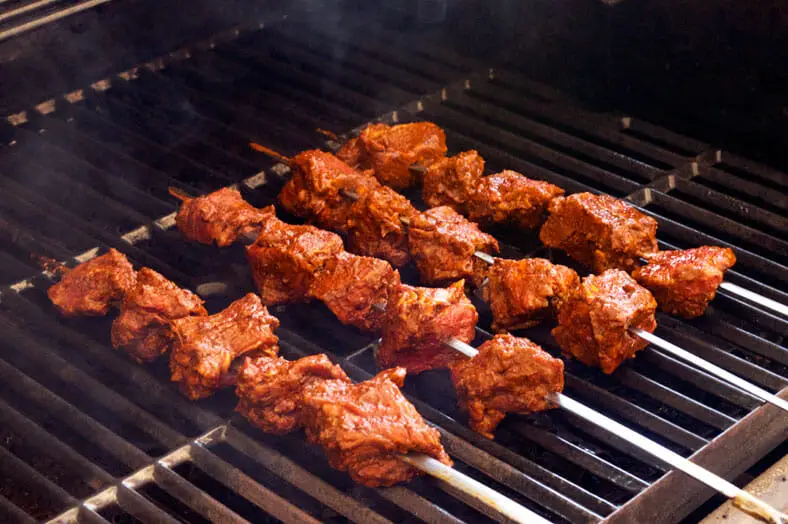 Skewers with beef pieces grilling over medium-high heat on the grill