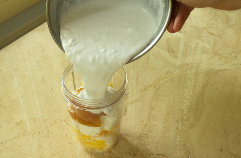 Coconut milk being added to coconut, honey and mango before being blended and added to the smashed watermelon