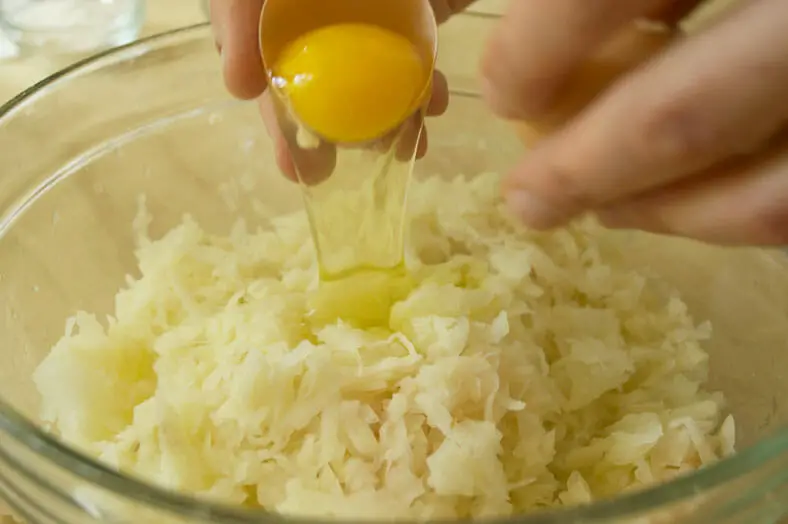 Mixing eggs with grated onions and potato