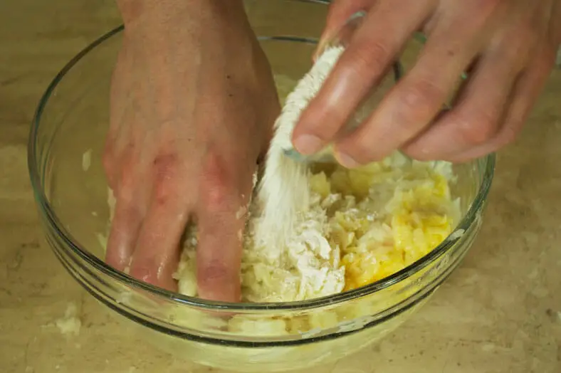 Mixing eggs with grated onions and potato for Belarus sausage stuffed Potato Pancake (Draniki)
