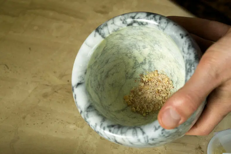 Grinding Mahlab seeds in mortar and pestle for dough 