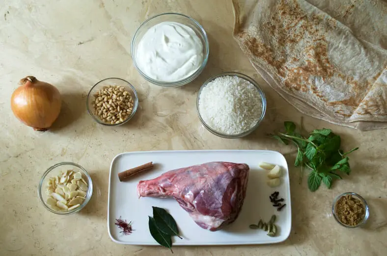 Ingredients - meat, onion, rice, yogurt, spices, mint, skinned almonds, curry leaves, cinnamon stick, saffron strands