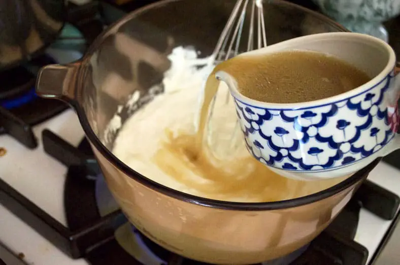 Adding the broth into warm yogurt to create a rich gravy sauce