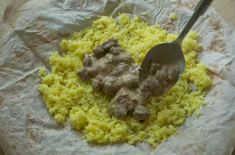 Assembling the Jordanian Mansaf dish - lamb, yogurt and rice pilaf