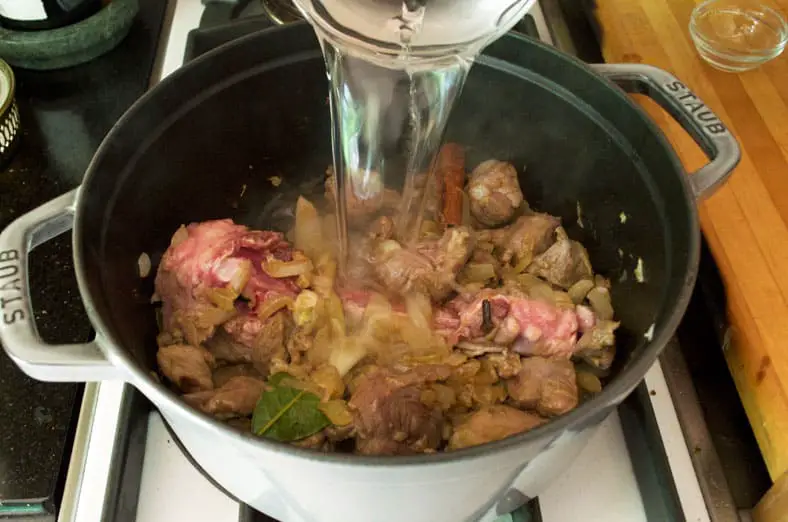 Adding water to a base of sauteed onions, garlic, lamb and spices to create the stew or broth for the Jordanian food