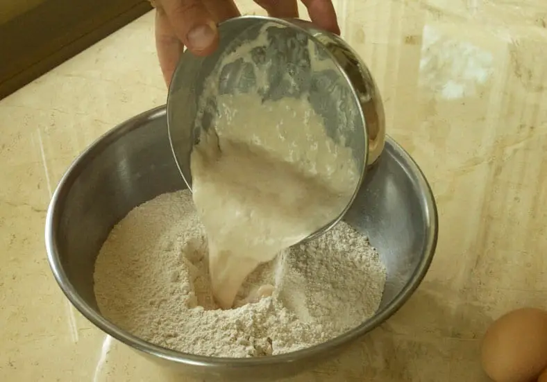 Making dough for cheese bread by adding yeast to flour