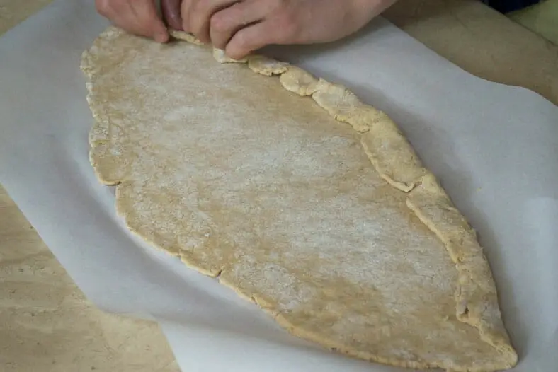 Shaping dough into a boat shape using hands