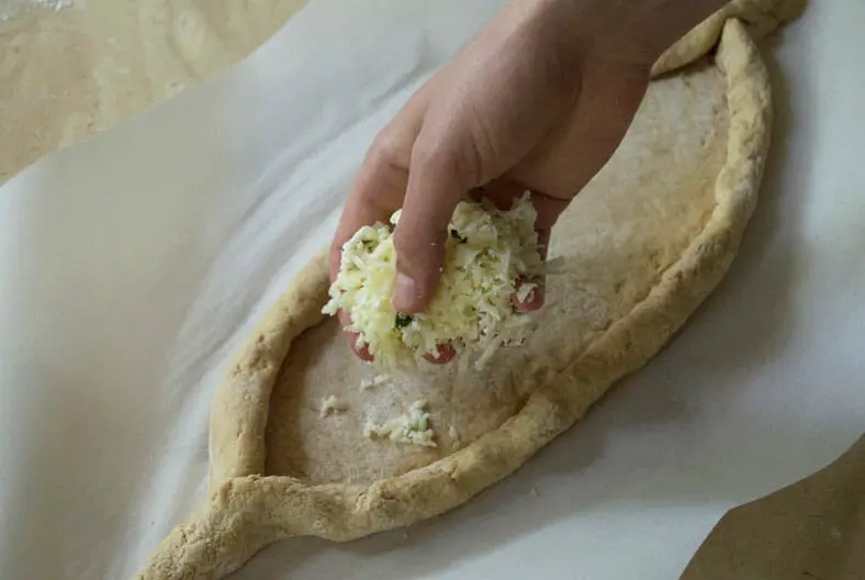 Adding cheese into the bread boat (Khachapuri - Georgian Cheese Bread)