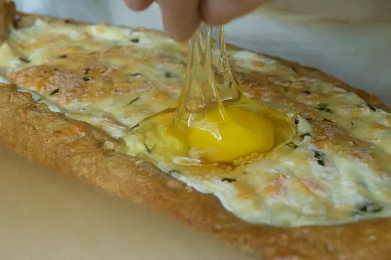 Cracking an egg over a half baked bread