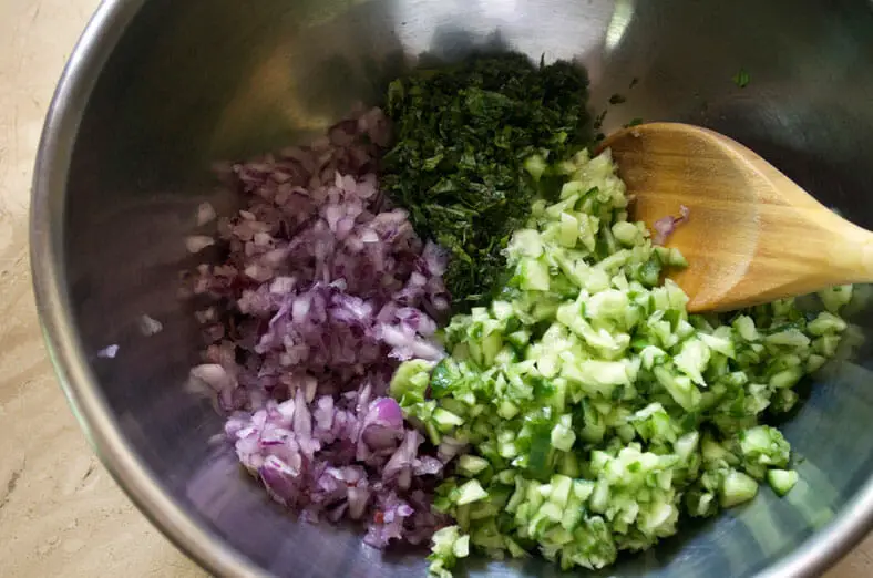 Mixing parsley, cucumber, red onion in a bowl with spoon