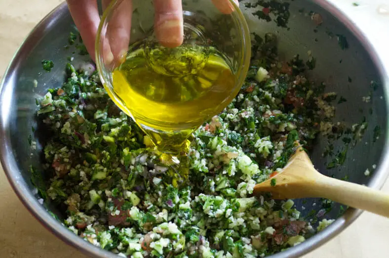 Adding olive oil to the Syrian Tabouli - parsley, cucumber, bulgur, red onion, tomato salad