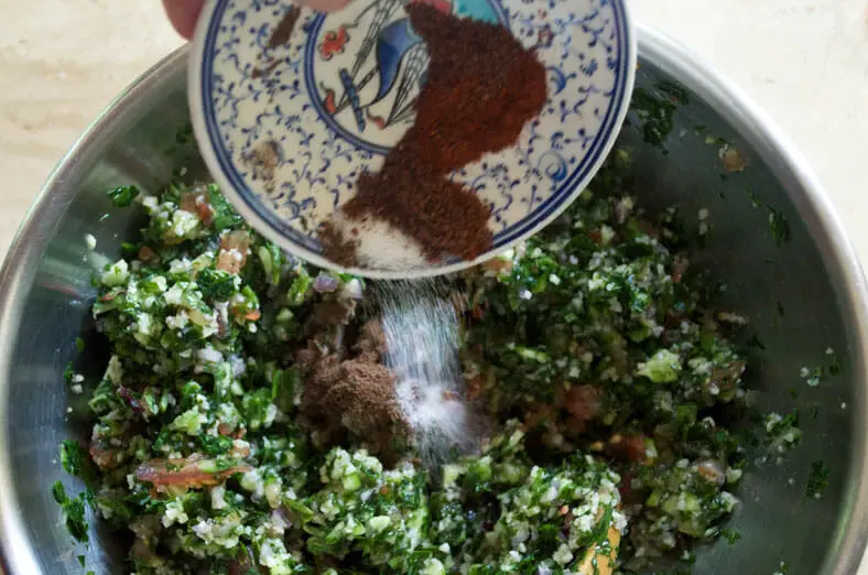Adding sumac, all spice and salt to the Syrian Tabouli - parsley, cucumber, bulgur, red onion, tomato salad