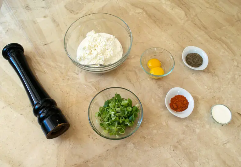 The ingredients before being mixed into the cheesy filling for nalysnyky (Ukranian crepes). Here you see cottage cheese, eggs, scallion greens, black pepper, cayenne, and whole whipping cream