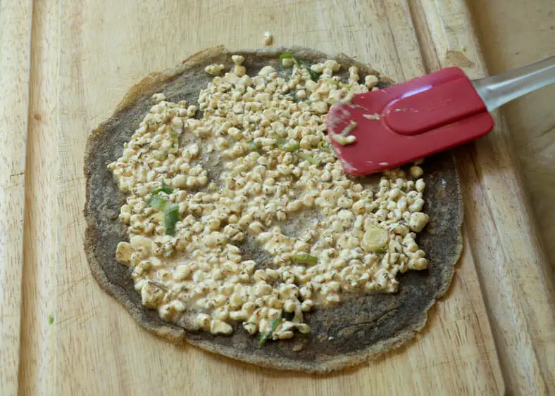 Spreading the cheesy filling (eggs, milk, herbs, scallions, cottage cheese) on to the surface of each crepe