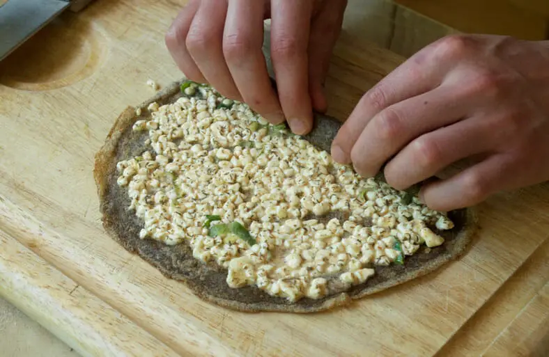 After spreading the cheesy filling (eggs, milk, herbs, scallions, cottage cheese) on to the surface, roll up each nalysnyky (Ukrainian crepe) and place in baking dish