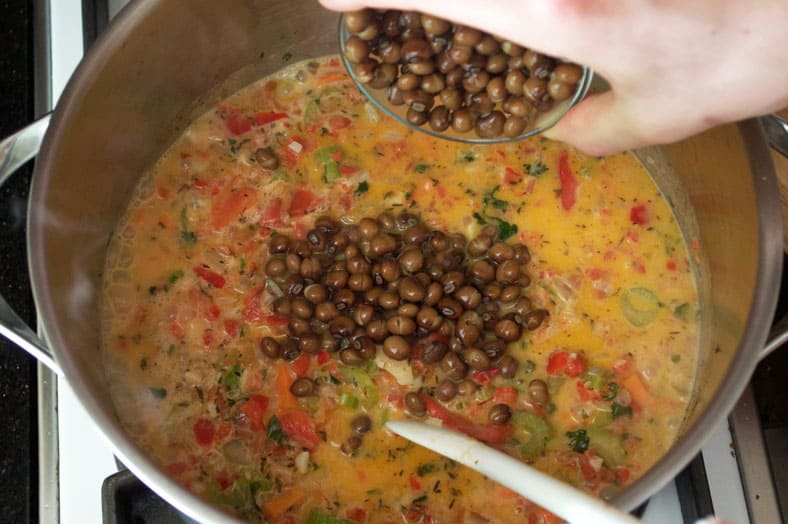 Adding pigeon peas to vegetable and coconut stew