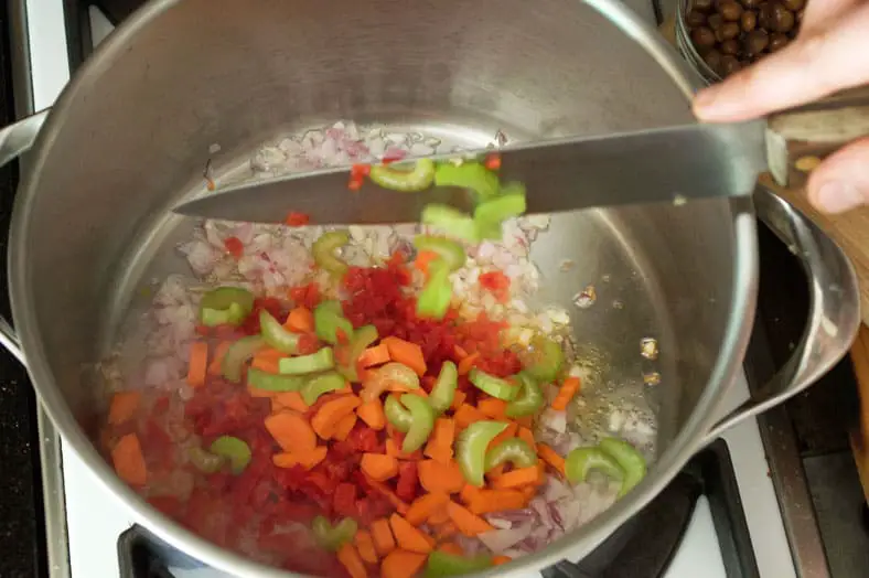 Adding red pepper, carrots and celery to pan for sofrito