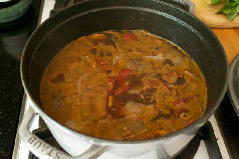 Making Pochero, a Filipino pork stew, with the beef stewing with tomatoes, onions, garlic and ginger