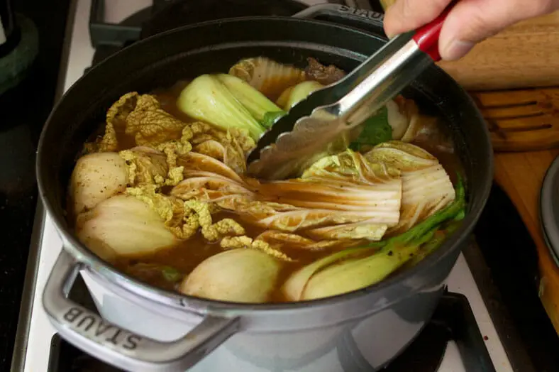 Dipping the cabbage leaves inside stew with tong
